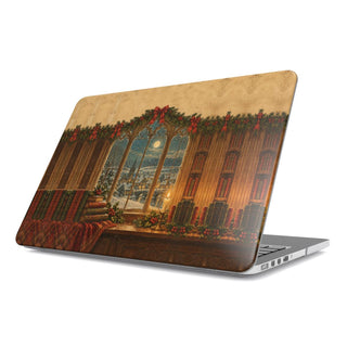 Christmas Library Window MacBook case — arched library window with snowfall, candle, holly and old books, hard-shell laptop cover, angled lid view