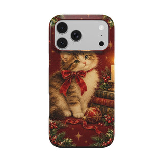 Christmas Cat phone case — fluffy kitten with a red bow beside a candle and stack of books, MagSafe iPhone case, front view