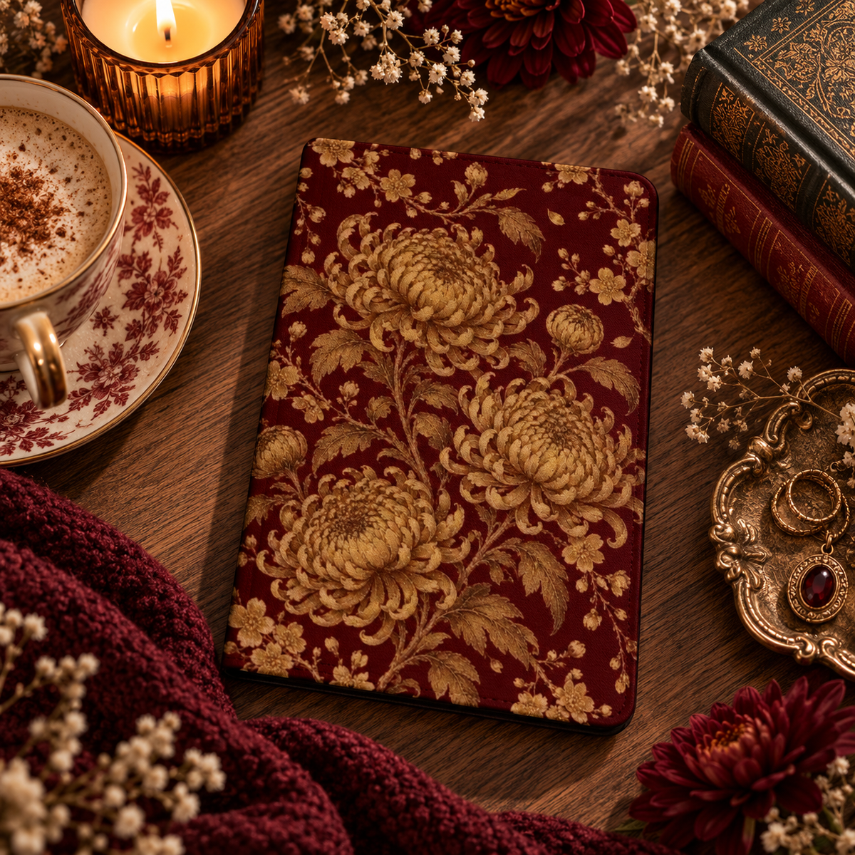 Gilded Chrysanthemum Kindle case — gold chrysanthemums on burgundy, styled with a latte, candle and old books